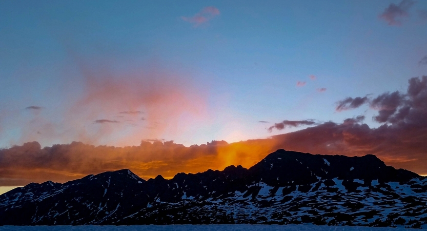 the sun rises behind a mountainous ridge